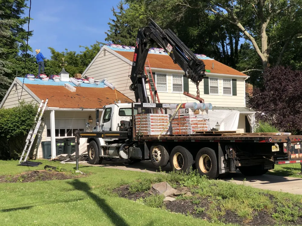 Crane truck delivering shingle bundles to a job site
