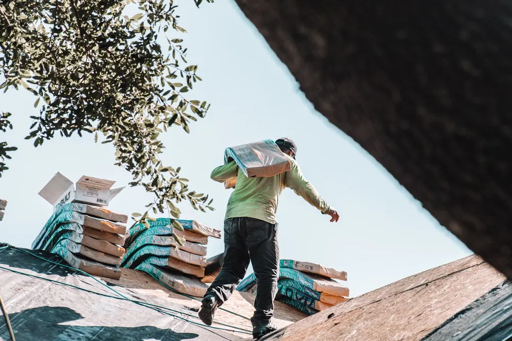 Roofer carrying shingles on a roof